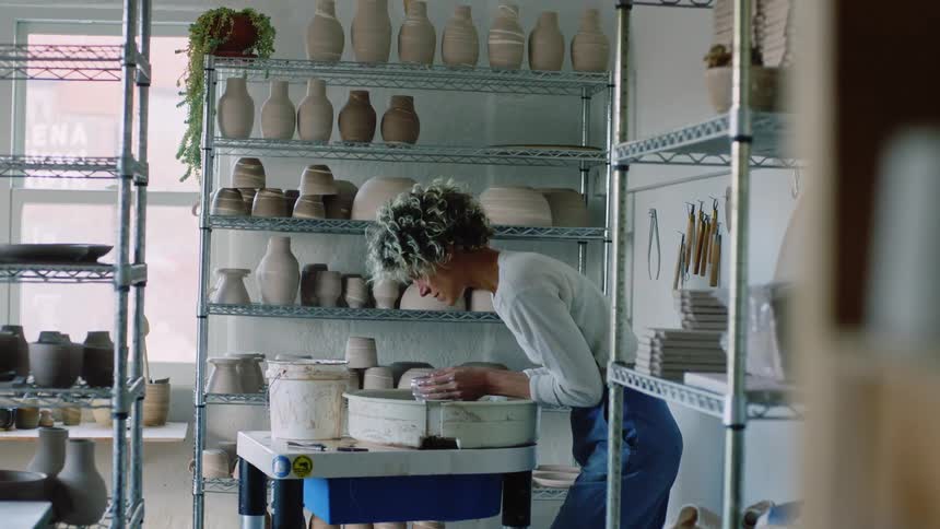 Woman inside an indoor space carrying out manufacturing in a handmade clay vase
