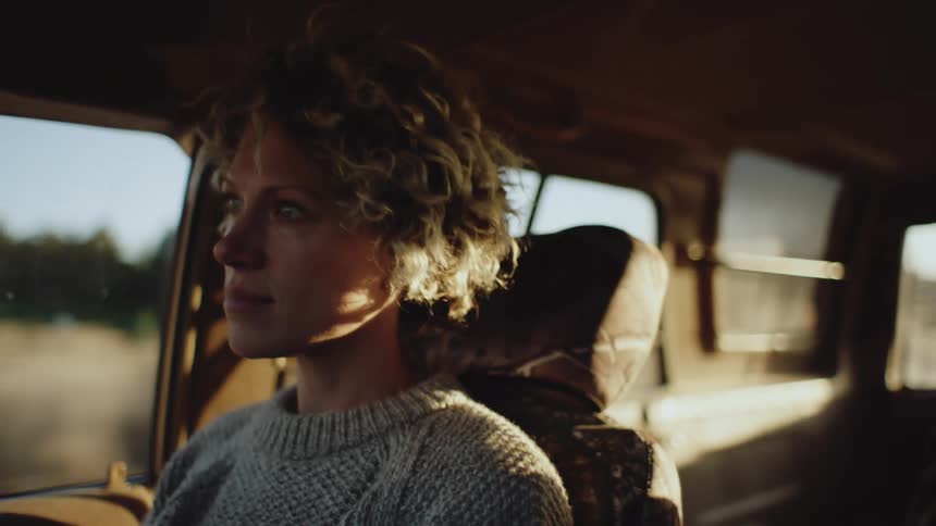 Woman sits in vehicle traveling through rural countryside