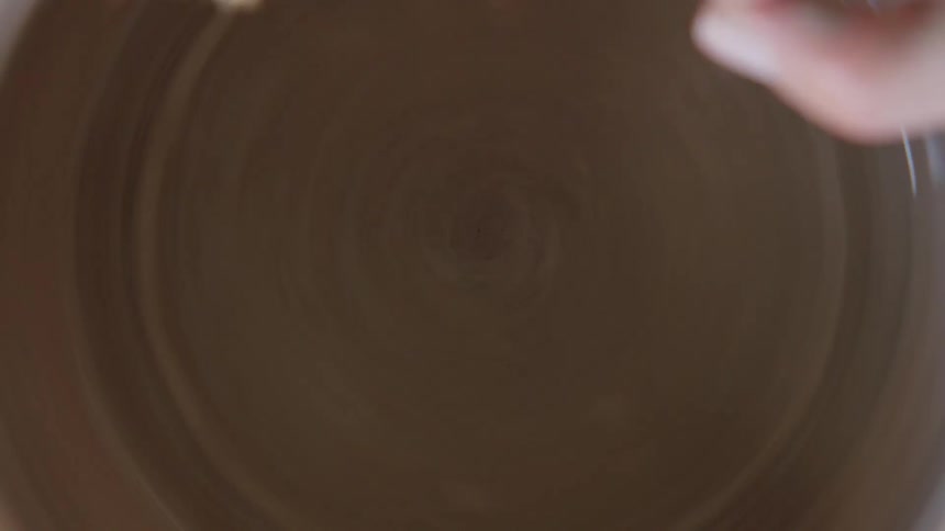 A person pouring water into a molded clay bowl