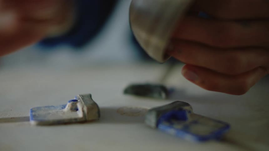 A woman stamps a piece of clay