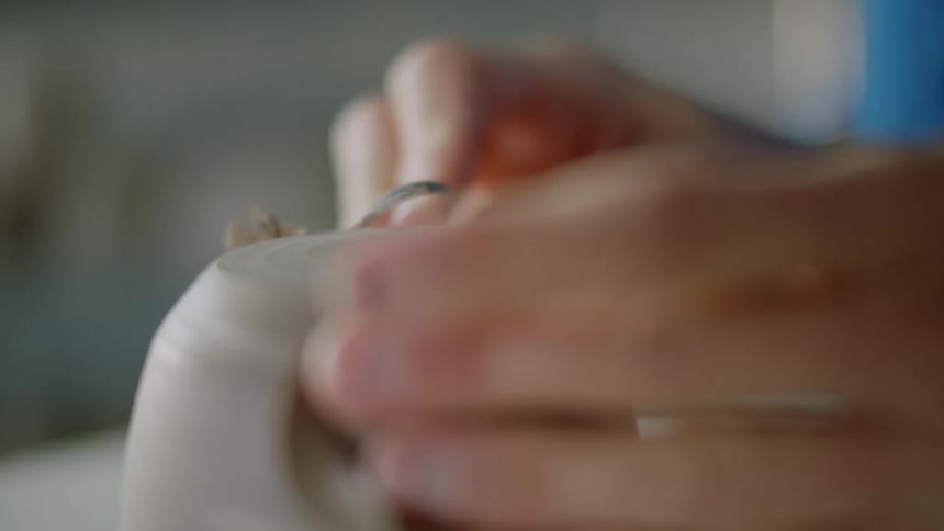 Closeup of a womans hands modeling a small clay vase