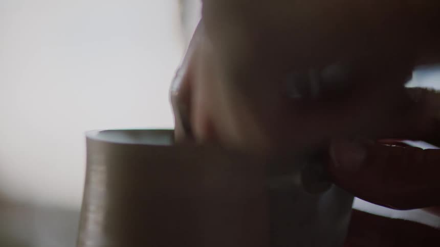 A hand shaping a piece of spinning clay