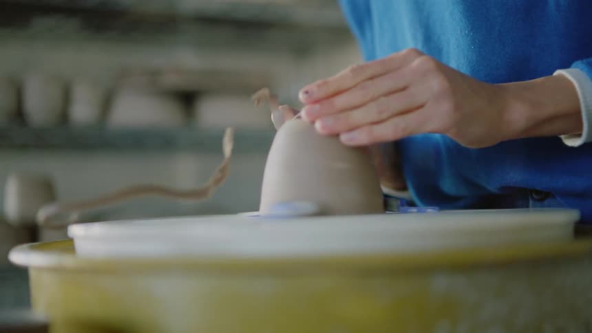 Womans hands molding a small clay vase