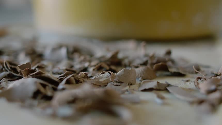 Clay shavings fall onto flat surface near yellow container