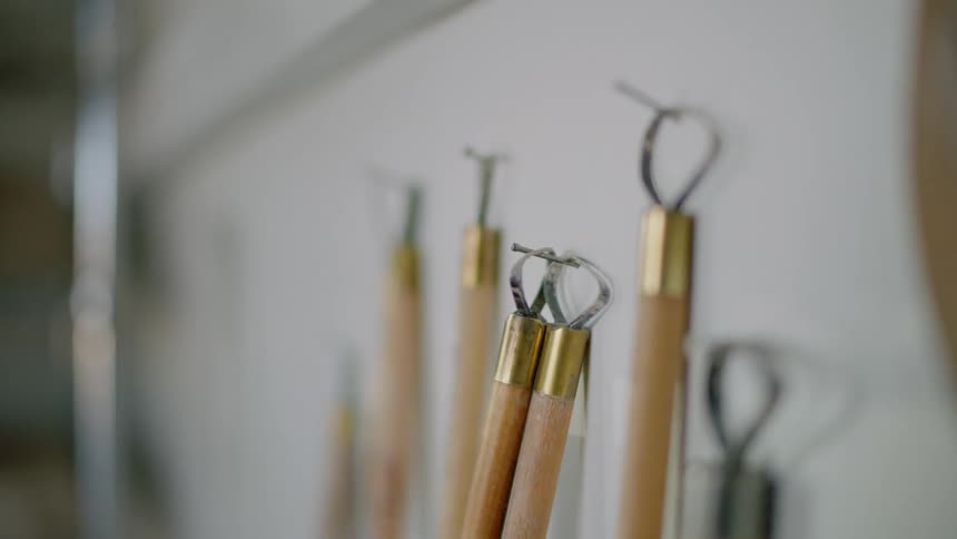 Several small pottery tools hang from nails protruding from the wall