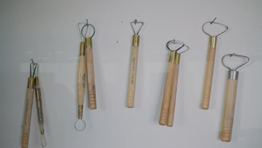 Several tools used for pottery hang from nails on the wall