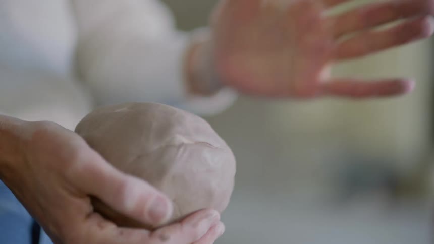 A person moving around a large ball of clay