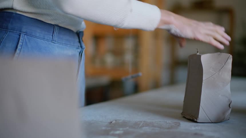 A woman slices up a block of clay