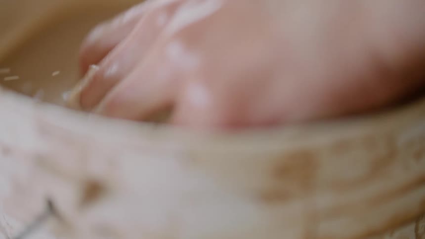 A liquid with sand at the bottom and a human hand wets the hand in this liquid and it moves