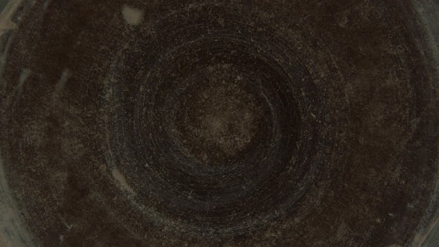 Closeup of a spinning metallic object and a womans hand wiping it with a cloth