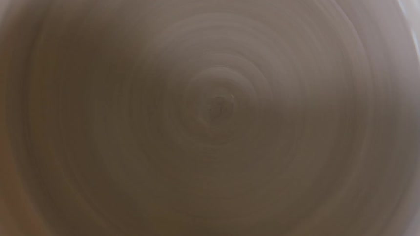 A pottery wheel spins with clay rotating around in a circle