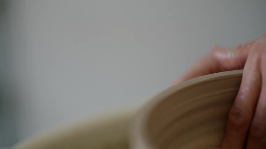 Hands of someone sculpturing a bowl indoor