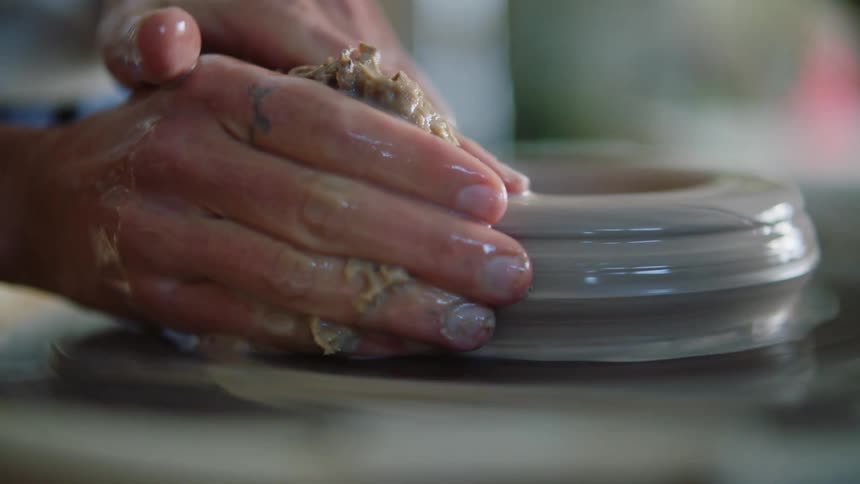 Closeup of a woman hands modeling a small clay vase