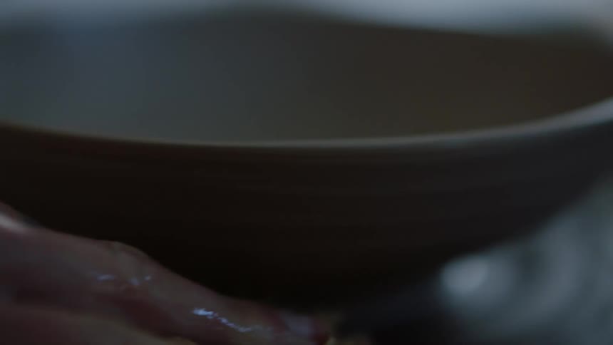 A person molding a clay bowl