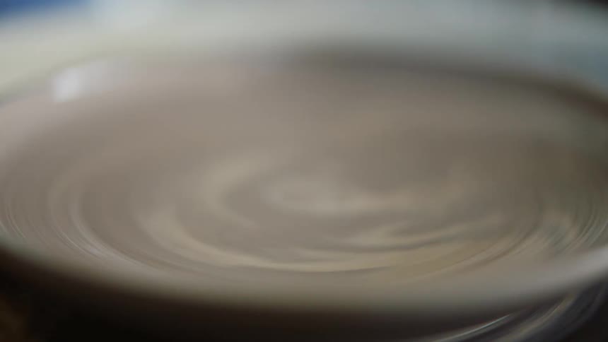 Potter shapes clay dish with a sponge