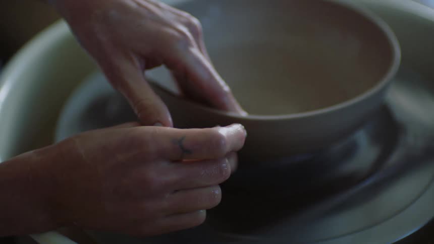 Hands of a woman modeling a clay and porcelain vase
