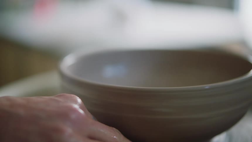 Closeup on a porcelain pot with a womans hands modeling