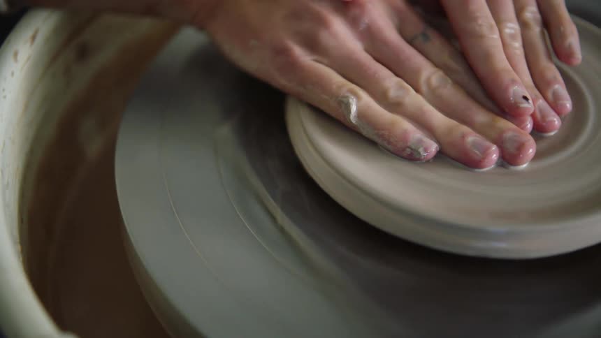 Hands of a female making a bowl on a sculpting wheel
