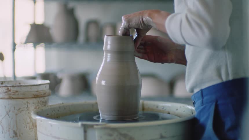Lady making a vase on the sculpting wheel during the day
