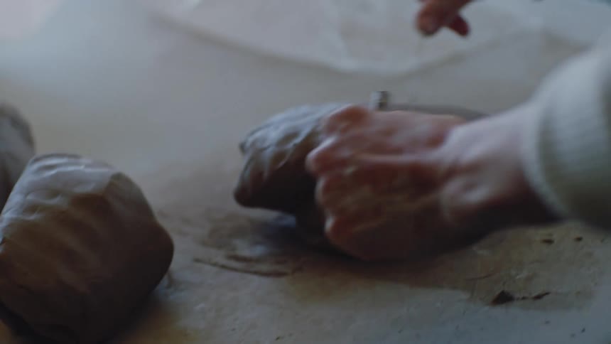 A person is kneading some clay balls and then cutting them with a thread