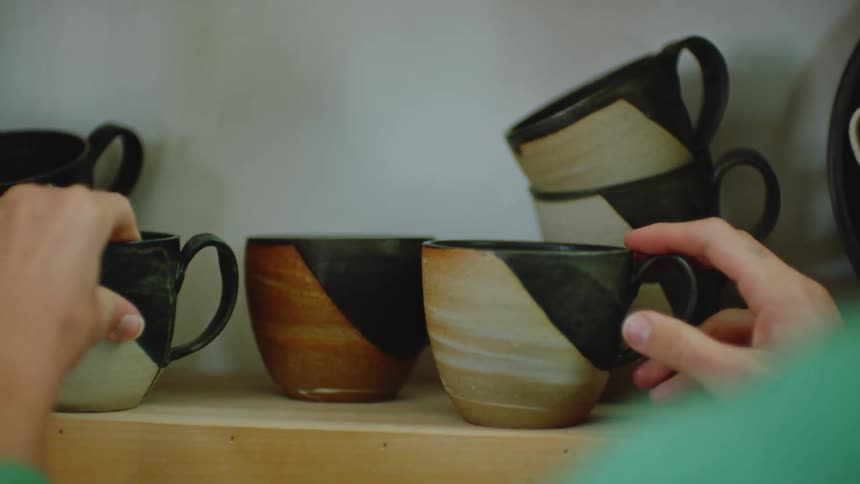 Womans hands arranging porcelain cups on a shelf