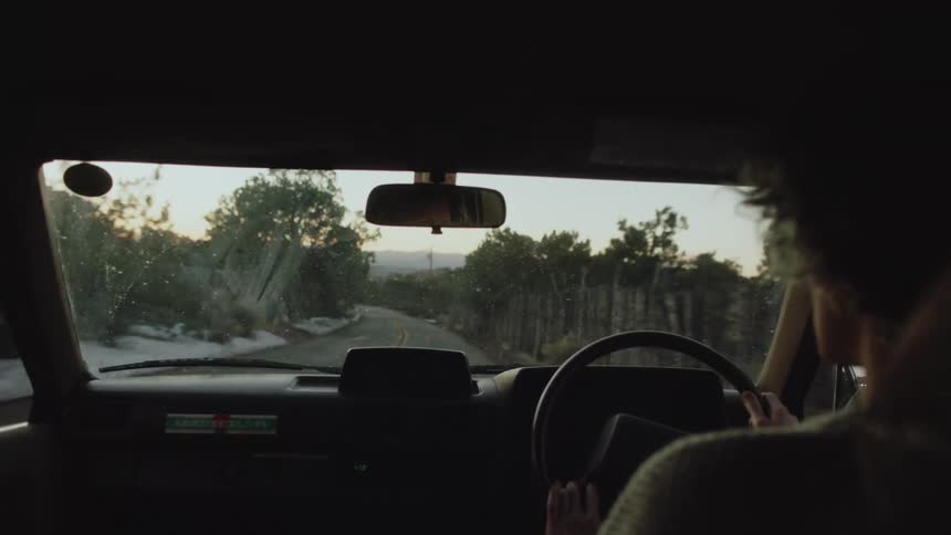 A white woman drives a car down a road