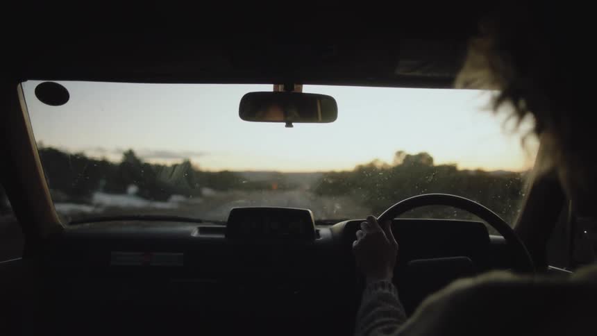 Lady driving a car on the road at sunset