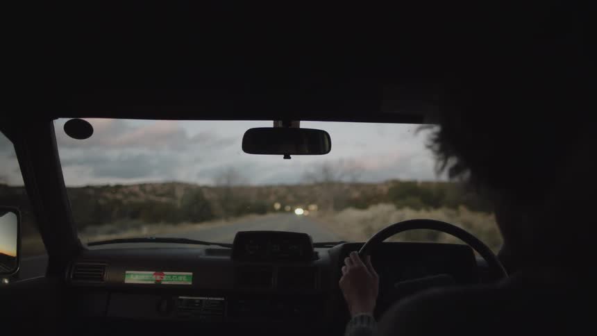 A female driving car on the road at sunset