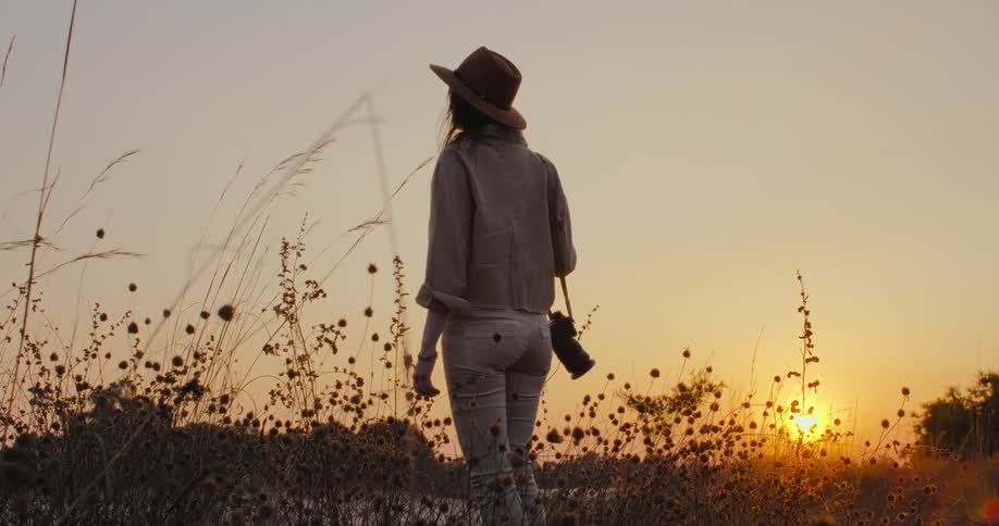 A photographer in a meadow admiring the sunset