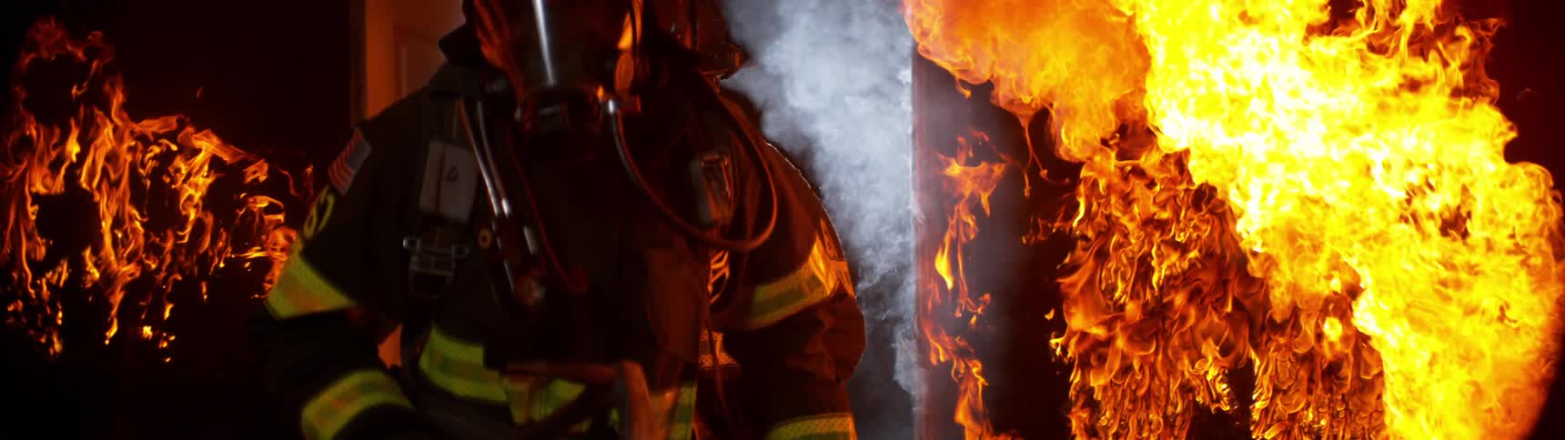 Two firefighters enter a room filled with flames