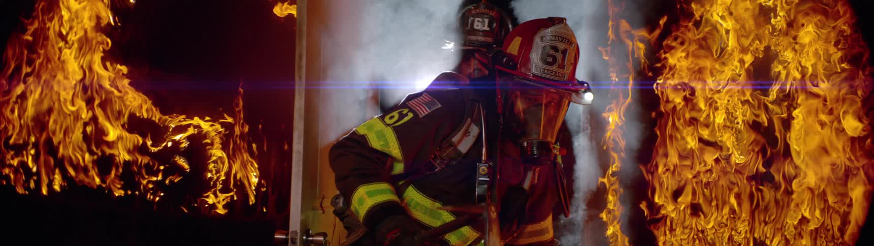 A firefighter passing through a door and on both sides there is a lot of fire burning the place