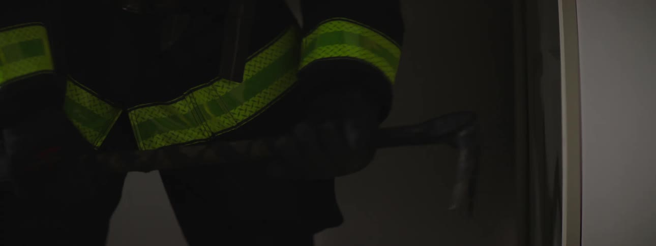 Firefighters trying to break down a door in a house