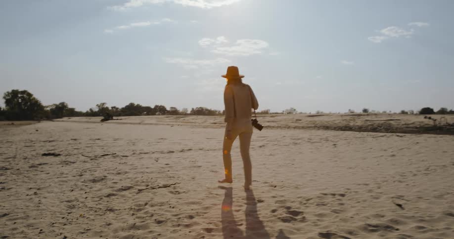 A woman is walking in the desert with a camera in her hands on a hot daya woman is walking in the desert with a camera in her hands on a hot day