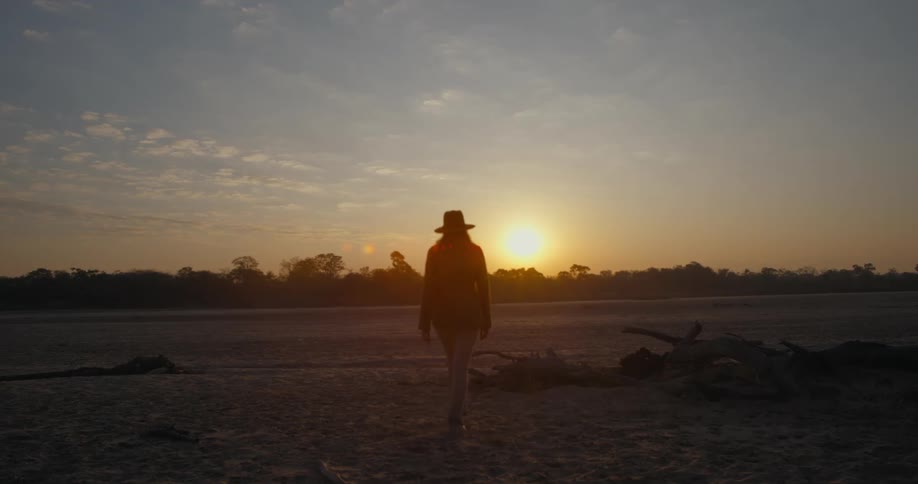 A woman walks across a flat dirt terrain