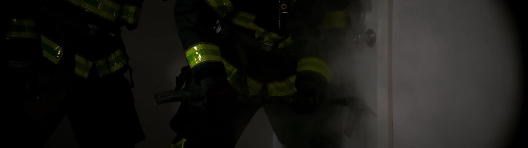 Firefighters with a tool pushing against the door in order to break down