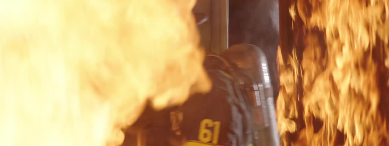 Two firefighters fixing a door and entering a house that is on fire