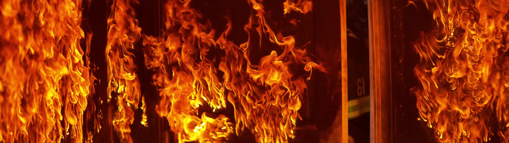 A firefighter burst through a door and into a room engulfed in flames