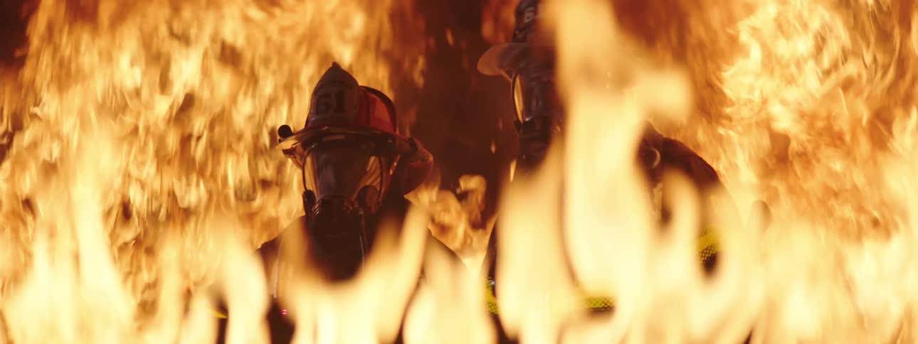 Firefighters in the middle of the flames of a fire