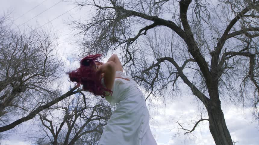 Woman dancer dancing in white dress in the open on a cloudy day