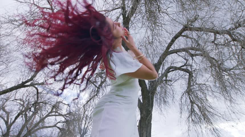 A girl twirls her head around outdoors