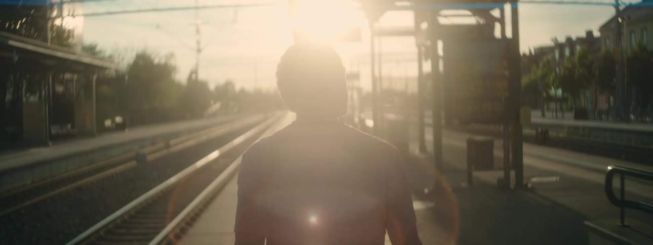 Back of a man walking near the rail line at sunset