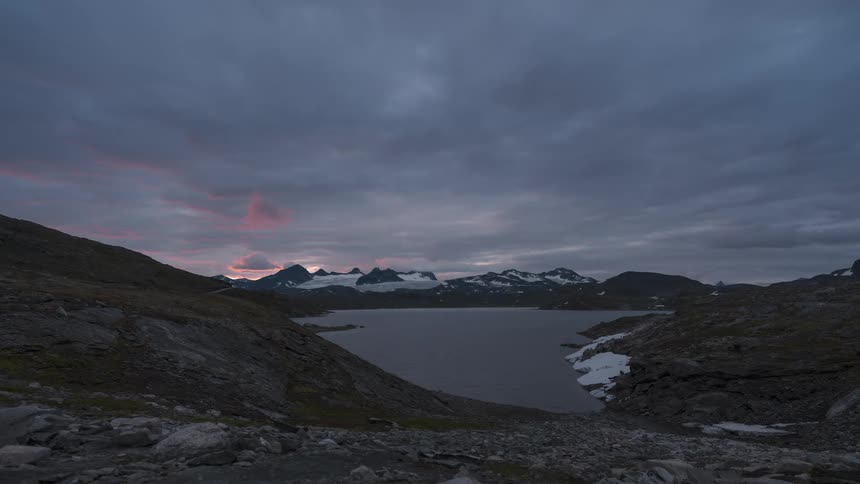 A lake surrounded by snowy mountains at dusk