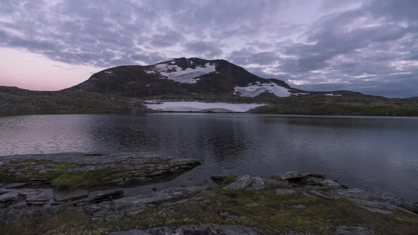 A lake that is reflecting a mountain behind it and the snow on the surface of that mountain