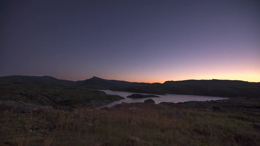 An aurora appears over a mountain and lake