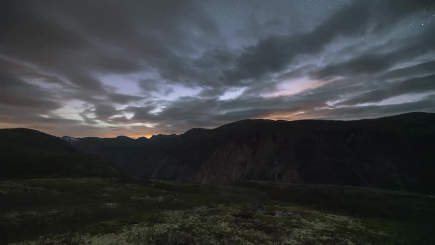 Clouds move across a mountain range at all times of the day and night