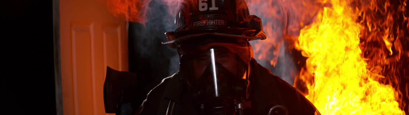 Firefighter with oxygen mask and protective clothing entering a fire at night