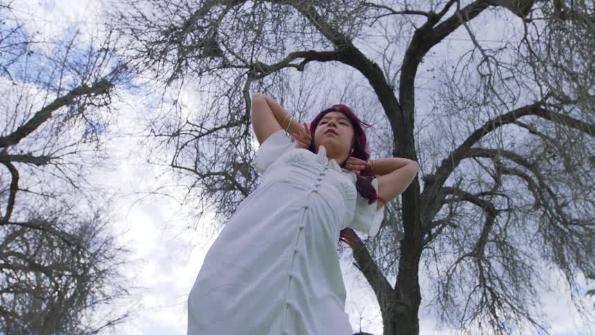 Young man and woman wearing a long white dress in nature dancing