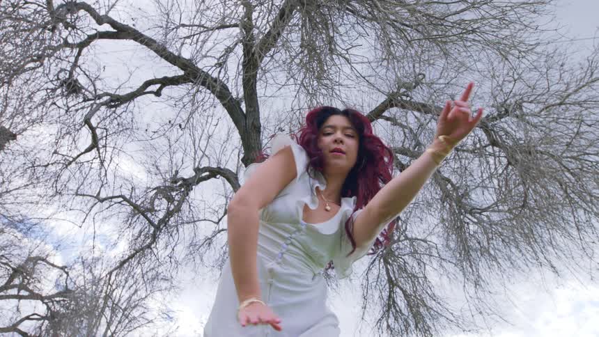 A woman dancing in front of a large tree