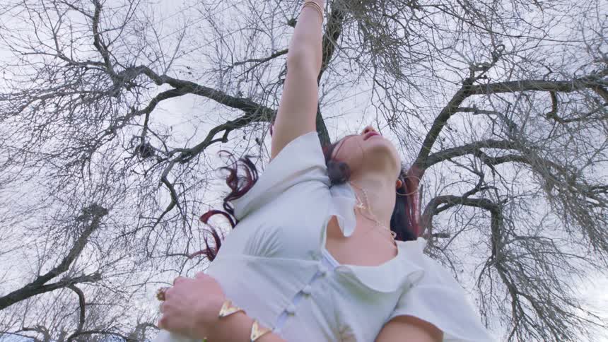 A woman is dancing under a tree