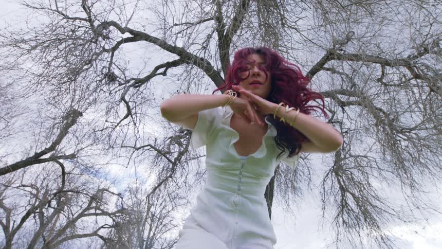 A woman dancing in front of a large tree
